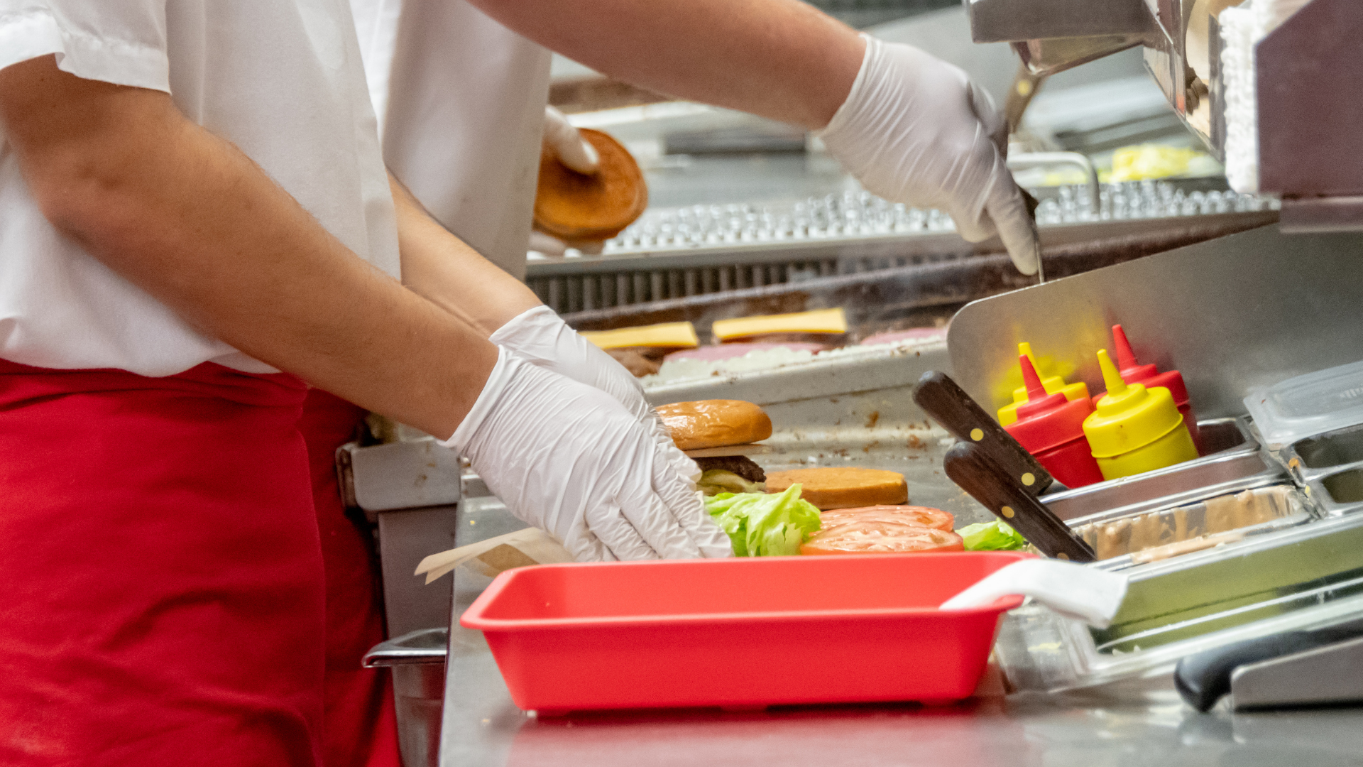 Quick-service kitchen crew assembling burgers on the line