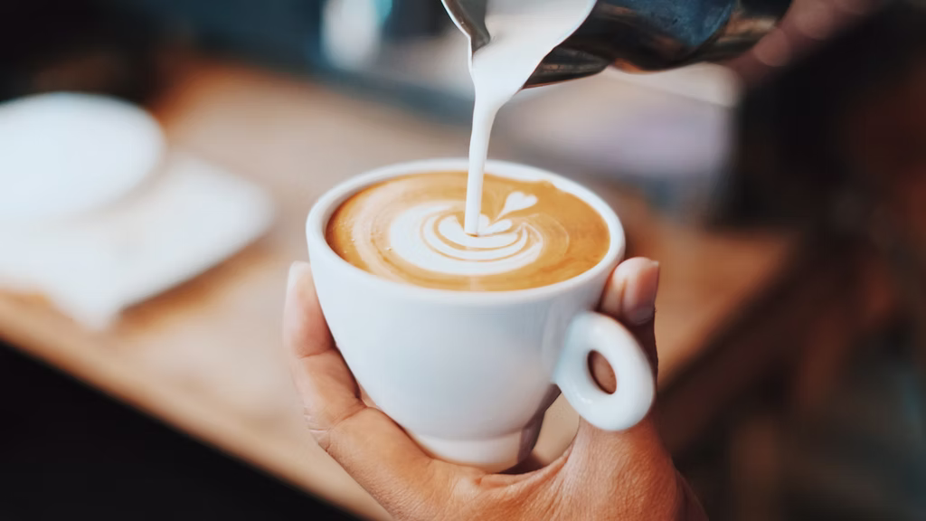 A barista pouring latte art for a specialty coffee customer