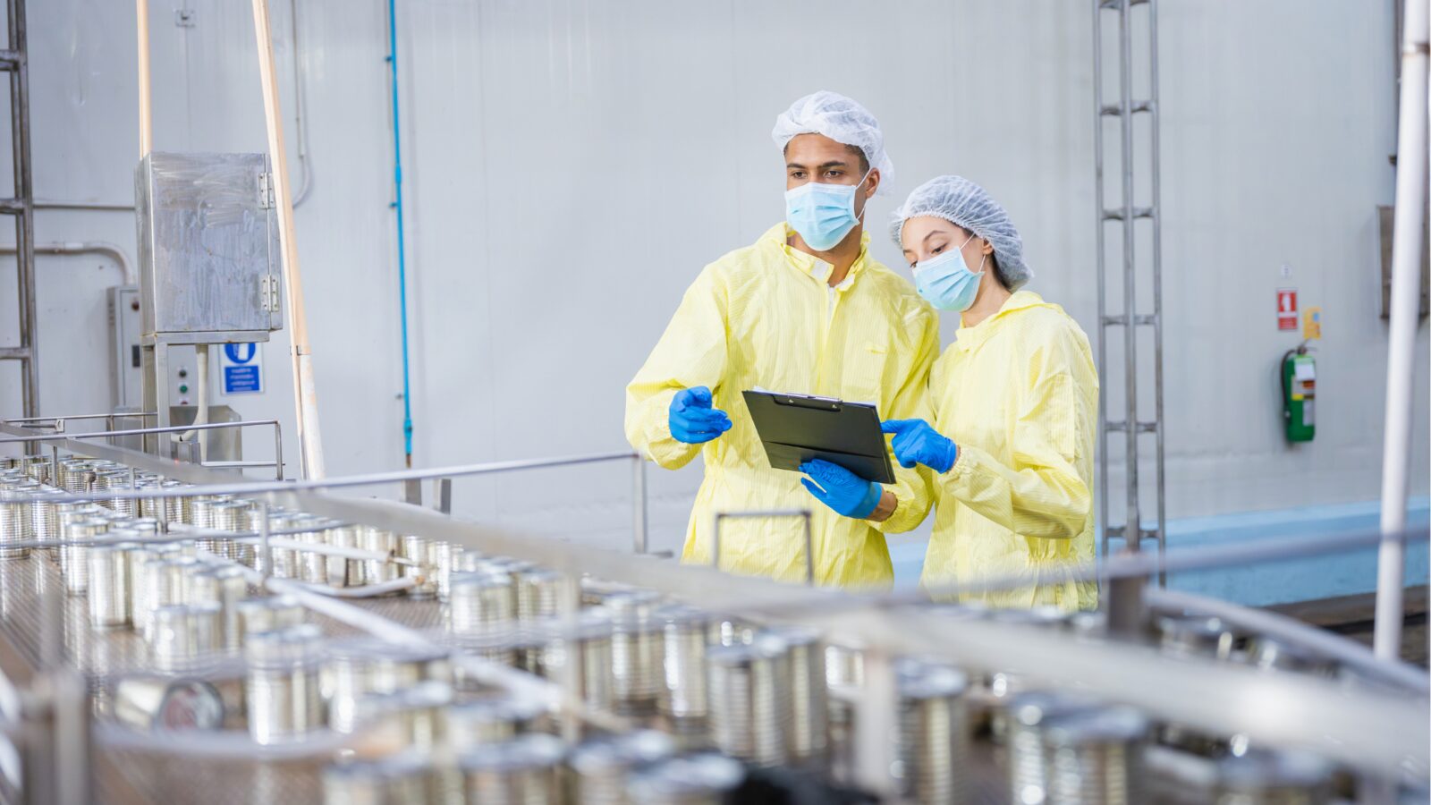 Two technicians reviewing output on a canning production line